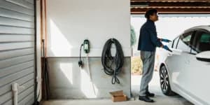 Man plugging an EV into a home level 2 charger after installation.