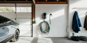 A home EV charger installed on a garage wall next to an electric car.